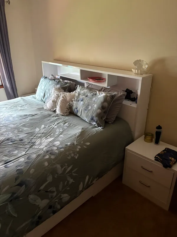 The same bedroom after the clean: bed made with cushions arranged, bedside table cleared