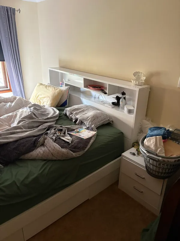 Bedroom before the clean: unmade bed, bunched doona and clutter on the bedside table